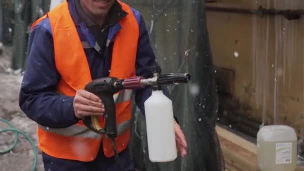 SAINT PETERSBURG, RUSSIA - DECEMBER 15, 2018:Construction man worker wearing uniform holds water spray gun on snowing day — Stock Video
