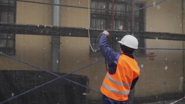 Sint-Petersburg, Rusland-15 december 2018: Bouwman arbeider draagt uniforme handen over water sproeipistool omhoog door touw — Stockvideo