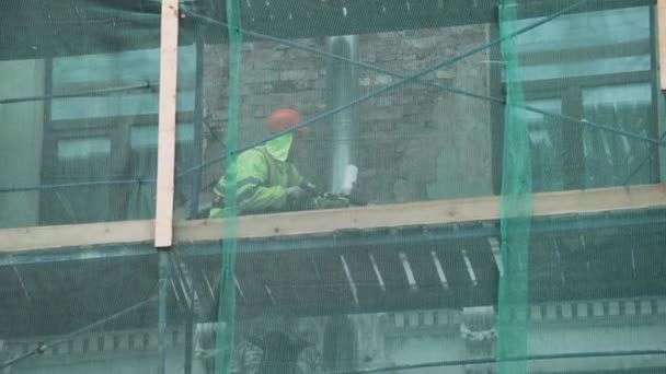 SAN PETERSBURG, RUSIA - 15 DE DICIEMBRE DE 2018: Trabajadores de la construcción en trabajo uniforme sobre andamios cubiertos con red verde — Vídeo de stock