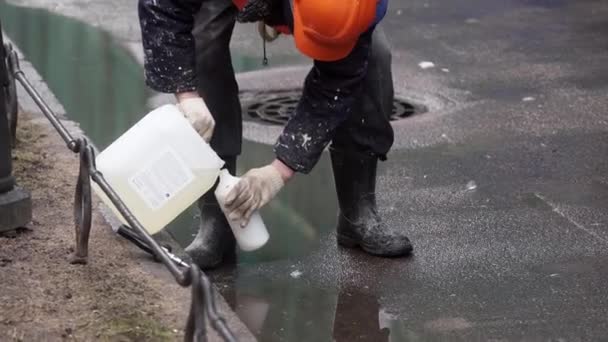 Sankt Petersburg, Russland - 15. Dezember 2018: Bauarbeiter in orangefarbener Uniform und Helm gießt Flüssigkeit in die Flasche. — Stockvideo
