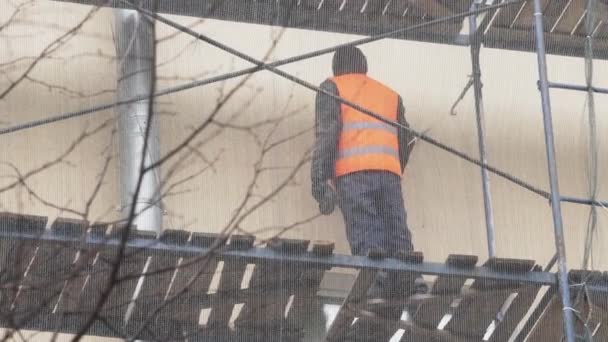 Saint petersburg, russland - dez 15, 2018: männlicher arbeiter in uniform zerkratzt wand mit hammer auf baugerüst — Stockvideo