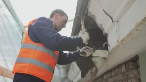 Saint petersburg, russland - 10. april 2018: asiatischer männlicher arbeiter in orangefarbener uniformweste löst schmutzige alte hölzerne wand. — Stockvideo