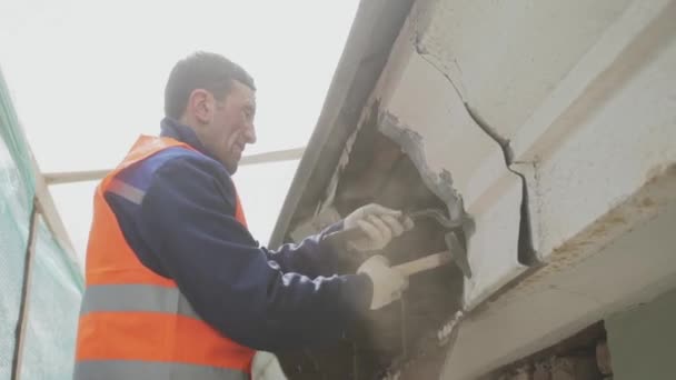 SAN PETERSBURG, RUSIA - 10 DE ABRIL DE 2018: Hombre trabajador en uniforme naranja y casco desmonta sucia pared de madera vieja . — Vídeos de Stock