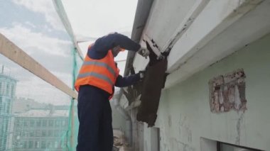Saint Petersburg, Rusya - 10 Nisan 2018: Turuncu güvenlik kıyafeti içinde Asyalı işçi bina kirli eski ahşap duvar tatili.