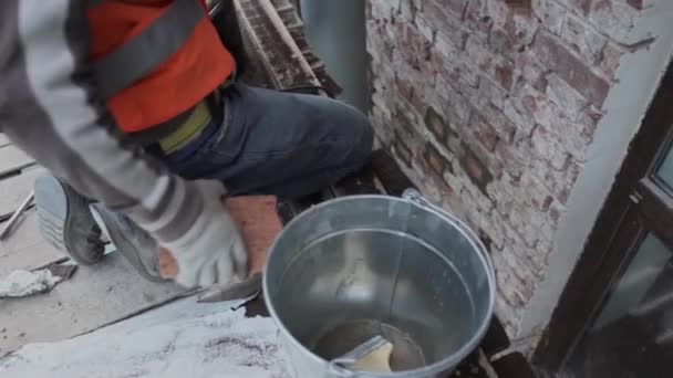 Санкт-Петербург, Росія-10 квітня 2018: будівельник працівник кладе цеглу в стіну фасаду і штукатурки його з великим ножем spackle — стокове відео