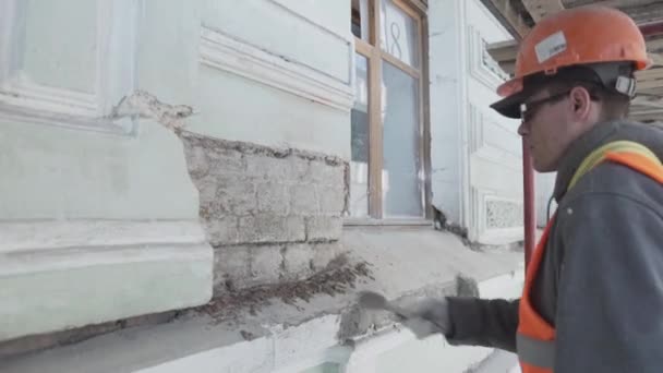 サンクトペテルブルク、ロシア - 4月 10, 2018: 男性労働者は正確に大きなペイントブラシでレンガの壁の作品をペイントしています. — ストック動画