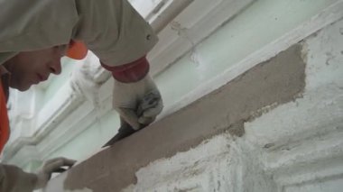 Saint Petersburg, Rusya - 10 Nisan 2018: İnşaat güvenliği üniforması giymiş işçi spatula aleti ile duvar sıvalar.