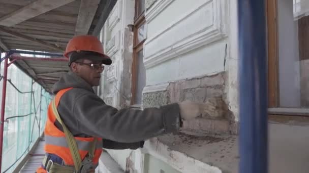 САЙНТ-ПЕТЕРБУРГ, РОССИЯ - 10 апреля 2018 года: Работник-строитель красит кирпичную стену большой кистью . — стоковое видео