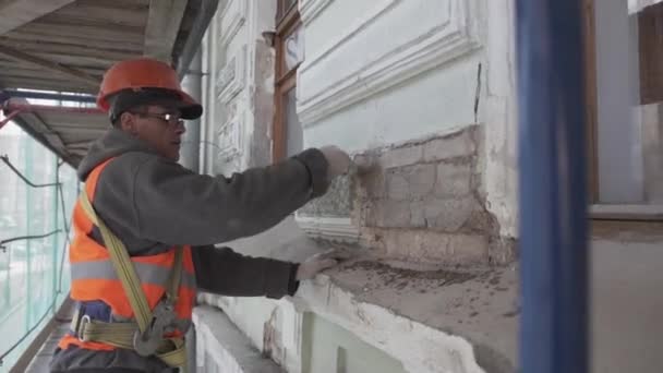 SAINT PETERSBURG, RUSSIE - 10 AVRIL 2018 : Un ouvrier de la construction peint un mur de briques avec un gros pinceau . — Video