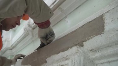 Saint Petersburg, Rusya - 10 Nisan 2018: Beyaz erkek işçi spatula aleti ile turuncu üniforma sıvaduvar koymak.