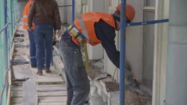 Saint Petersburg, Rusya - 10 Nisan 2018: Yeşil ağla kaplı iskelede tek tip çalışan konstuksiyonlu erkek işçiler