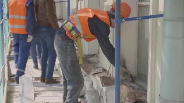 サンクトペテルブルク、ロシア - 4月 10, 2018: 緑の網で覆われた足場の均一な作業をする一部の男性労働者 — ストック動画