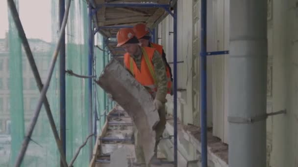 СЕНТ-ПЕТЕРБУРГ, РОССИЯ - 10 апреля 2018 года: Зрелый работник в оранжевом костюме обдирает грязную старую ржавую металлическую часть стены . — стоковое видео