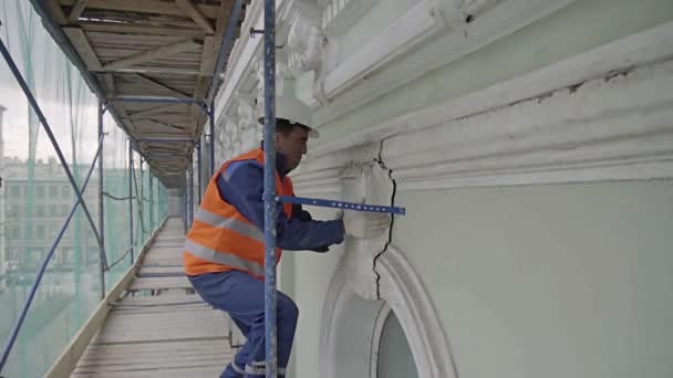 Saint Petersburg, Rusya - 10 Nisan 2018: Turuncu kıyafetli Asyalı erkek işçi beyaz duvarın büyük ağır kısmını ayırıyor. — Stok video