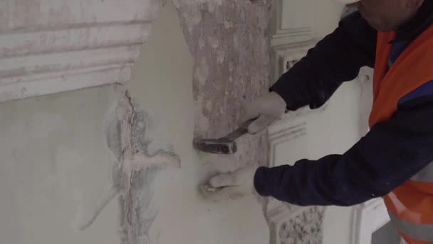 St. petersburg, russland - 10. april 2018: männlicher arbeiter in orangefarbener weste und weißem helm schlägt mit hammer teil der weißen wand. — Stockvideo
