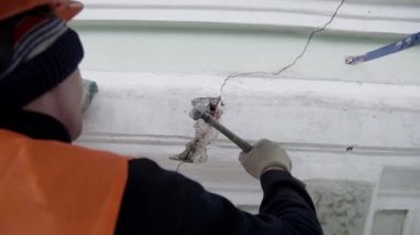 Saint Petersburg, Rusya - 10 Nisan 2018: Üniformalı donanımlı işçi, cephe duvarının bir parçasına vurmak için küçük çekiç kullanıyor