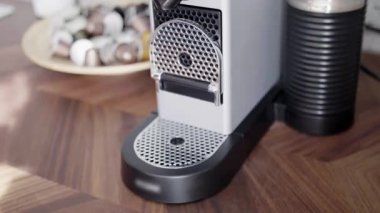 Birisi kapsüllü küçük otomatik kahve makinesinin tepsisine kırmızı fincan koyar.