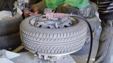 Adam araba teknisyeni otomatik onarım servis garajda tekerlek pompa lastik bitirir.