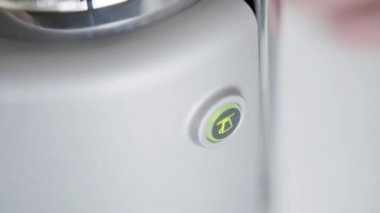 Someones parmak presler yuvarlak şekilli düğme, kompakt kahve makinesi açar.