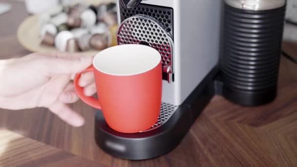 Qualcuno mano mette la tazza rossa su vassoio di piccola macchina del caffè con capsule . — Video Stock