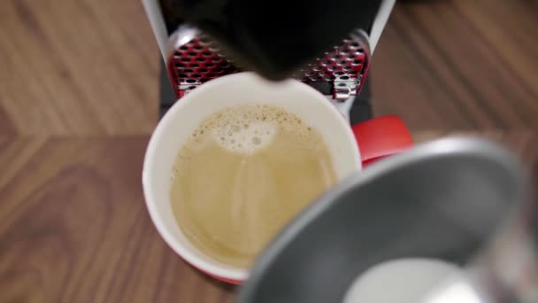 Mannetjes hand voegt melk toe aan rode beker met koffie geplaatst op dienblad met koffiemachine. — Stockvideo