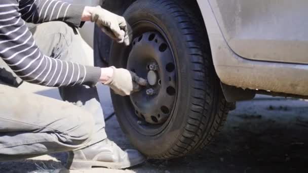 Hombre técnico de automóviles reemplaza neumático de la rueda del coche en la carretera en la calle en el día soleado — Vídeos de Stock