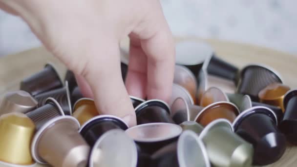 Guys hand takes black coffee capsule out of bowl with lots of other capsules. — Stock Video