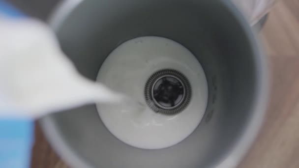 Leche que se vierte en espuma de leche eléctrica metálica con un pequeño batidor en la parte inferior — Vídeos de Stock