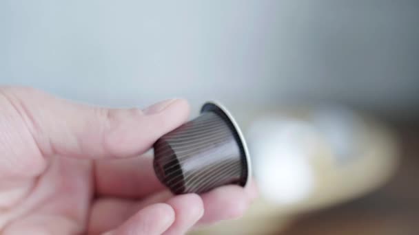 Mans hand holds small brown capsule with stripes of automatic coffee machine. — Stock Video