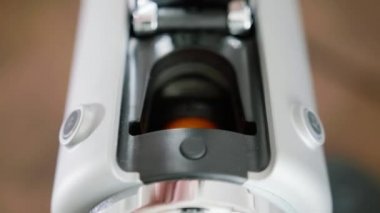Turuncu kapsül kompakt yeni gri otomatik kahve makinesi yuvasına yerleştirilir.