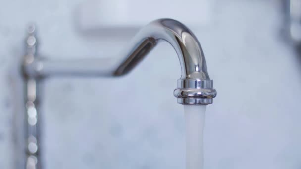 Sauberes Leitungswasser fließt aus neuem gekrümmten Wasserhahn in heller Küche. — Stockvideo
