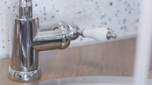 Close-upweergave van someones hand beweegt kraan kraan om het te openen zodat water kan stromen. — Stockvideo