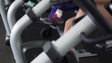 İki Fitness kadın bacaklar spor salonunda sabit döngüsü kardiyo egzersiz yapıyor.