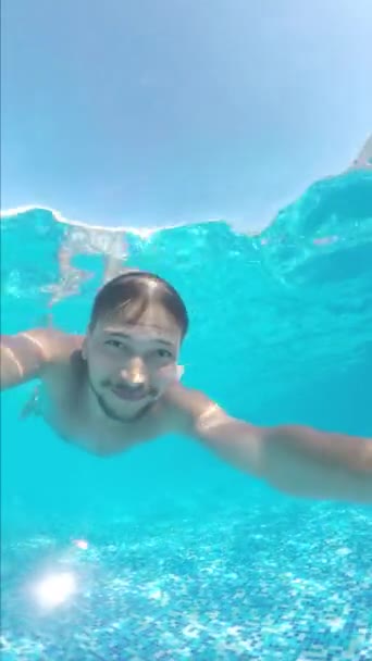 Bonito hombre barbudo está nadando bajo el agua en la piscina en el día soleado caliente . — Vídeos de Stock