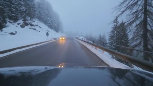 Dunkles modernes Auto bewegt sich auf Landstraße zwischen schneebedeckten Bäumen und Hügeln. — Stockvideo