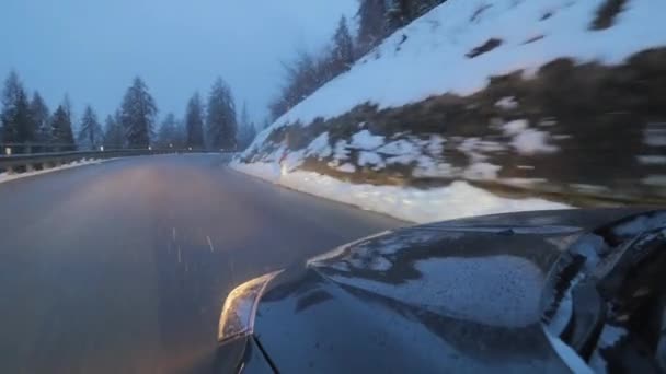 Coche a estrenar con faros encendidos en los movimientos en carretera de montaña a lo largo de árboles nevados — Vídeos de Stock