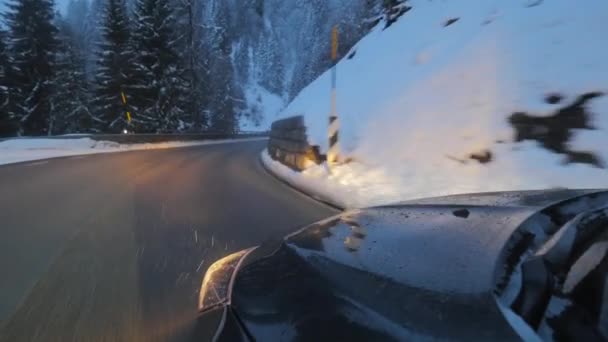 Moderno coche con faros encendidos se mueve por la carretera a lo largo de los árboles cubiertos de nieve y colinas . — Vídeos de Stock