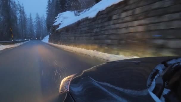 冬の日に山道を動くヘッドライト付きの黒い自動車. — ストック動画