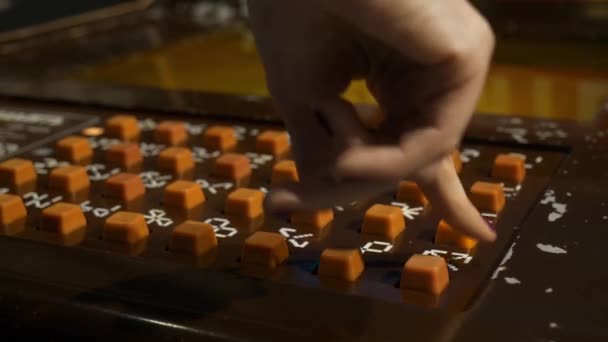 Vrouwtjes hand drukt Oranje knoppen op bruin panel van slot machine. — Stockvideo