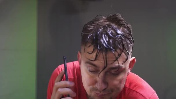 Exhausto sudando hombre de camiseta roja está haciendo cardio y hablando por teléfono . — Vídeos de Stock