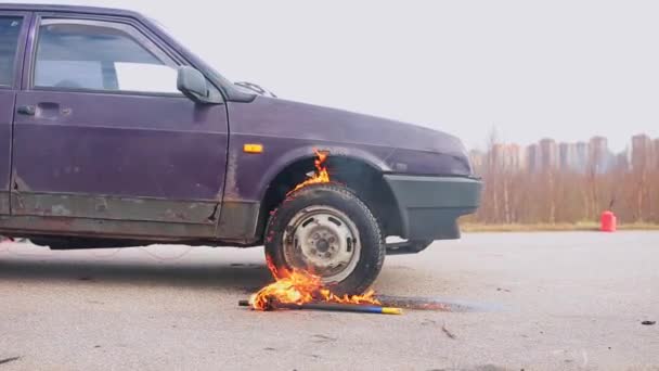 Régi rozsdás lila autó maradt elhagyatott úton égő kerékkel a hideg napon. — Stock videók