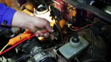 Adam işçiler eller araba motoru içinde sarı ve kırmızı kabloları sabitleme vardır.