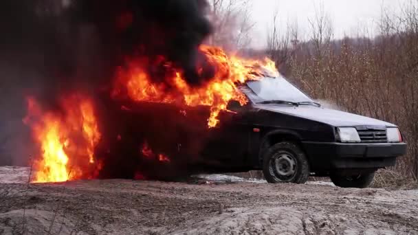 불의 거대한 흡연 불꽃은 버려진 먼지 도로에 남아 더러운 오래된 차를 태워 — 비디오
