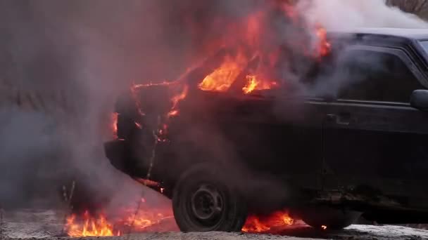 火災の大規模な喫煙炎は、さびれたほこり道に残された汚れた古い車を燃やす — ストック動画