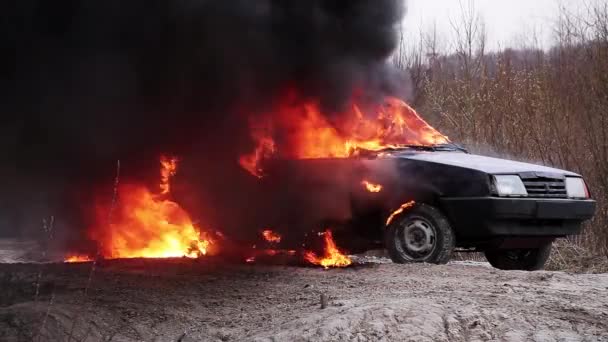 Enorm røykende flamme brenner fullstendig skitten, gammel bil som står igjen på grå vei – stockvideo