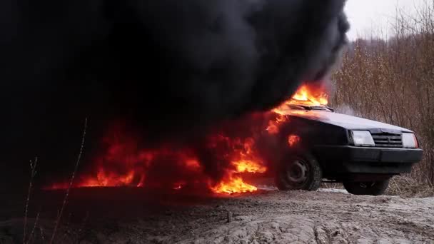 Grande chama fumegante de fogo queima completamente carro velho sujo deixado na estrada deserta . — Vídeo de Stock