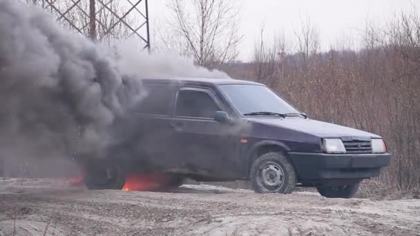 オープントランクは、汚れた古い車から大量に喫煙している無人のほこり道に残されています — ストック動画