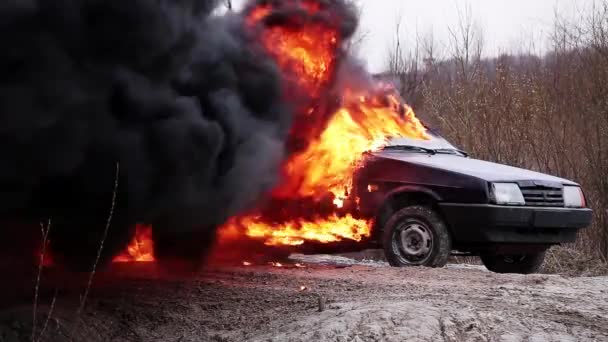 Grande chama fumegante de fogo queima completamente carro velho sujo deixado na estrada deserta . — Vídeo de Stock