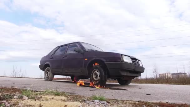Rozsda régi modell lila autó marad a szürke úton égő kerékkel a hideg napon. — Stock videók