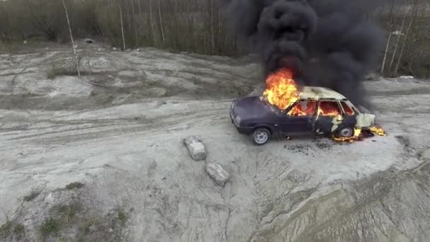 Opuszczone szare pole, gdzie ogromny płomień w pełni pali samochód i czarny dym idzie w górę — Wideo stockowe